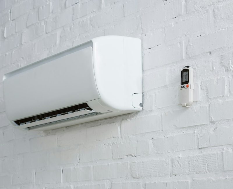 air-conditioner-hanging-on-white-brick-wall-with-remote-control.jpg